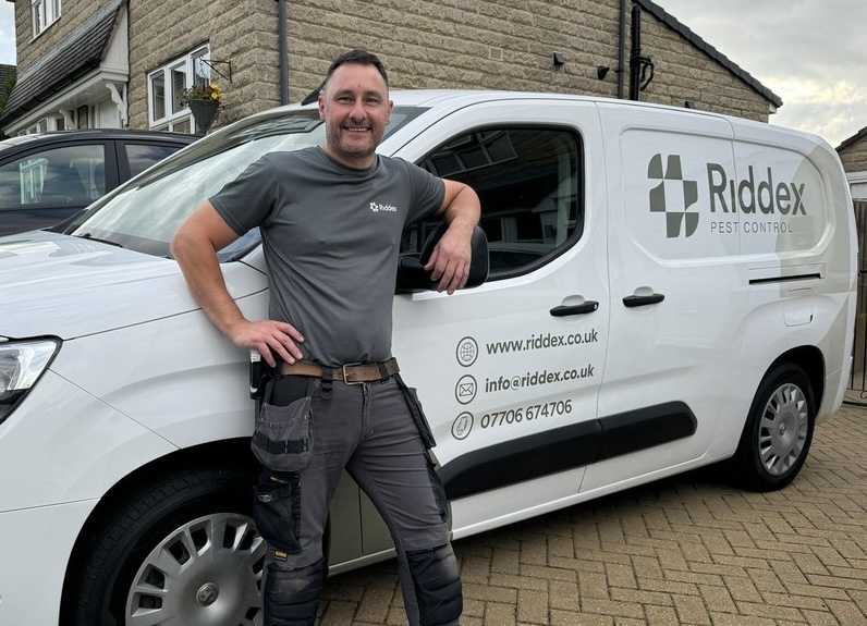 Pest controller leaning against branded van 